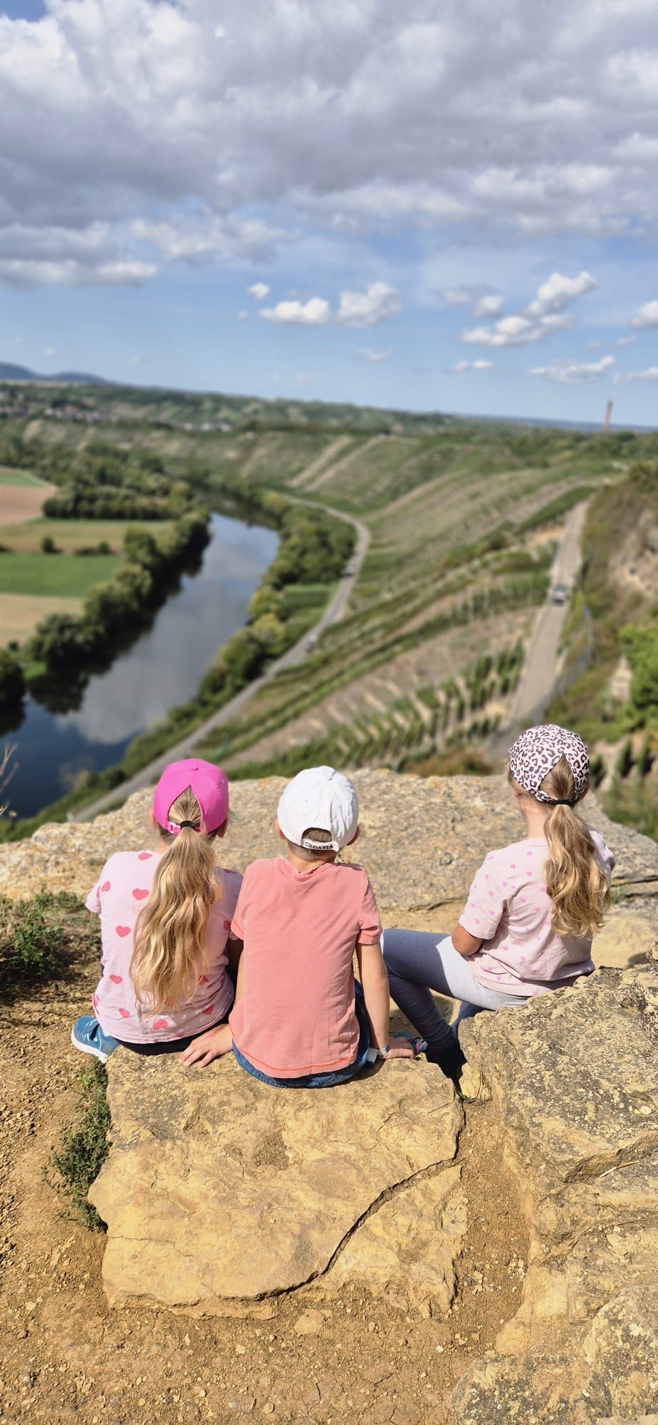 Drei unserer Kinder sitzen auf einem Felsen und blicken ins Tal
